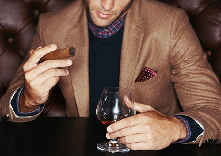 Man holding a cigar and a drink